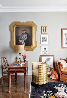 a living room filled with furniture and pictures on the wall next to a table in front of a chair