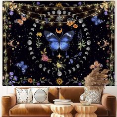 a living room with a couch, table and large butterfly wall hanging on the wall