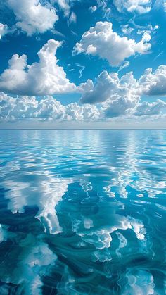 the sky and clouds are reflected in the calm ocean water on a clear, sunny day