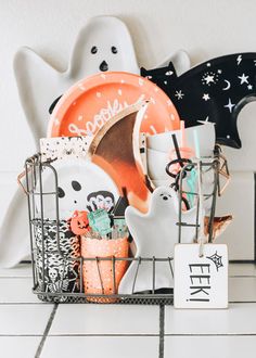 a basket filled with halloween items on top of a white tiled floor next to a ghost