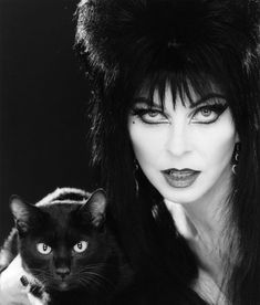 a woman with long black hair holding a cat