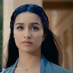 an image of a woman with blue hair looking at the camera while wearing a necklace