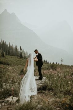 a bride and groom standing on top of a mountain