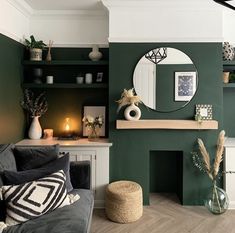 a living room with green walls and white trim on the fireplace, decorated with plants