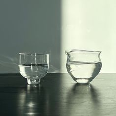 two glass bowls sitting on top of a wooden table next to each other with water in them