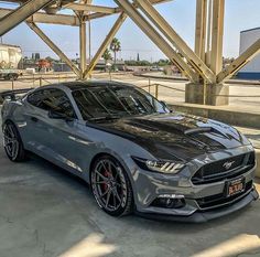 a silver mustang car parked under a bridge