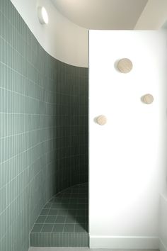 an empty bathroom with green tile and white walls, along with three round lights on the ceiling