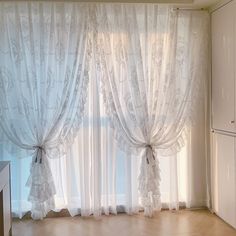 an empty room with white curtains and wooden floors