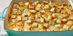 a blue casserole dish filled with cheese and bread croutons on a table