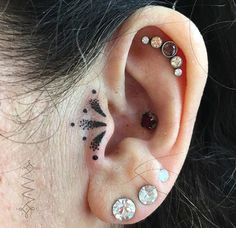 a woman with some piercings on her ear and behind the ear is a flower