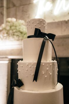 a three tiered white cake with black ribbon