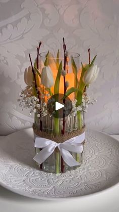 a vase filled with flowers sitting on top of a white table covered in lace and ribbon