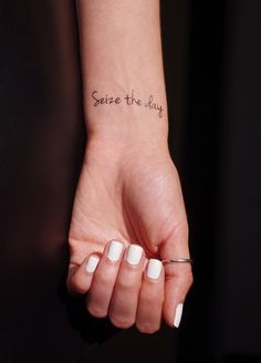 a woman's hand with a small tattoo on it that says, serve the day