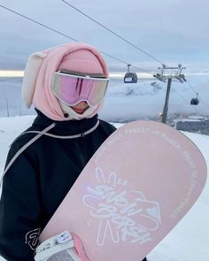 a person wearing goggles and holding a snowboard