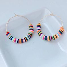 "These are weightless, trendy and so pretty! Gold plated hoops, weightless heishi beads and 2 gold textured beads make these earrings showstoppers! They measure approximately 2\" ." Nickel-free Heishi Bead Hoop Earrings, Trendy Small Hoop Earrings With Colorful Beads, Nickel-free Multicolor Heishi Beads Jewelry, Handmade Colorful Hoop Jewelry, Colorful Small Hoop Beaded Jewelry, Trendy Colorful Dangle Hoop Earrings, Trendy Hoop Earrings With Colorful Beads, Colorful Small Hoop Jewelry With Colorful Beads, Colorful Handmade Hoop Jewelry