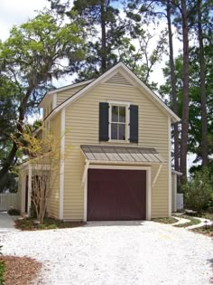 a yellow house with black shutters on the front and two garages on the side