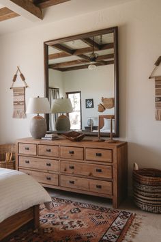 a bedroom with a dresser, mirror and lamp on the side table in front of it