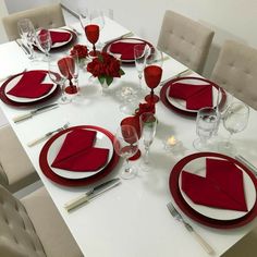 a white table with red napkins and place settings