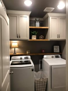 a washer and dryer in a small room with white cupboards on the wall