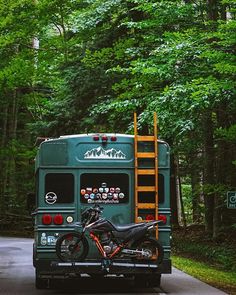 a motorcycle is parked on the back of a green bus in the middle of the road