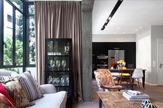 a living room filled with furniture and lots of windows next to a dining room table