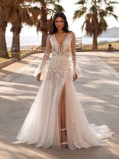 a woman in a wedding dress is standing on the sidewalk with palm trees behind her