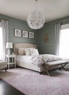 a bedroom with green walls, white furniture and a chandelier hanging from the ceiling