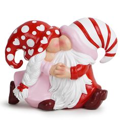 a red and white gnome figurine sitting next to a mushroom on its back