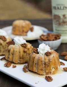 three bundt cakes sitting on top of a white plate with pecans around them