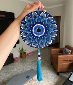 a person holding up a blue and white decorative object with tassels on it