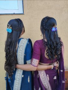 two women standing next to each other in front of a building with long dark hair