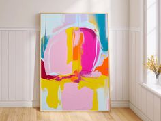 an abstract painting is displayed in the corner of a room with white walls and wooden floors