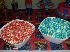 two white bowls filled with popcorn sitting on top of a red and blue table cloth