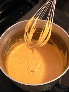 a whisk is being used to stir batter in a pot on the stove