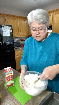 an older woman is mixing something in a bowl on the kitchen counter top with her hands