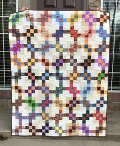 a person holding up a quilt made with squares and crosses on the side of a building