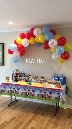 a party table with balloons and paw - fect decorations