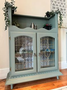 a blue cabinet with glass doors and plants on top