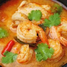 a bowl filled with shrimp and cilantro on top of a table