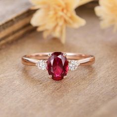 a close up view of a ring with a red stone and two diamonds on it