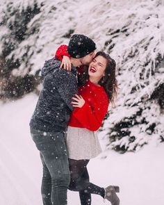 a man and woman kissing in the snow with trees covered in snowflakes behind them