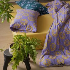 a bed sitting next to a potted plant on top of a wooden floor in front of a yellow chair