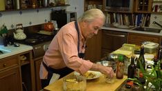 an older man in the kitchen preparing food on a cutting board with bowls and bottles