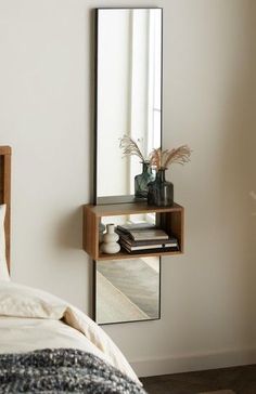 a bedroom with a bed, mirror and vase on the shelf in front of it