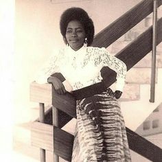 an old photo of a woman standing in front of a stair case with her hands on her hips