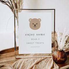 a sign with a bear on it sitting next to a vase and some dry grass