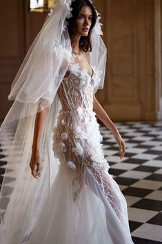 a woman in a wedding dress and veil walking on a black and white checkered floor