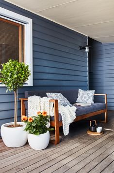 a couch sitting on top of a wooden deck next to potted plants