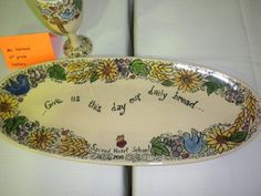 there is a decorative plate with flowers on it and a wine glass next to it