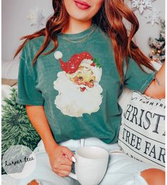 Add this vintage Santa shirt to your holiday wardrobe . This comfort colors shirt is guaranteed softness. Get into the Christmas season with our vintage Christmas shirt. This comfort colors tshirt will become your favorite.  SHIRT COLOR BLUE SPRUCE SHIRT INFO: ❤︎ SHIRT QUALITY  Comfort Colors Tee   100% ring-spun cotton  Medium fabric  Relaxed fit  Soft washed garment   Highly Durable ❤︎ PRINT QUALITY We use Direct to Garment Printing with high quality ink.  Colors shown on your monitor may diff Hipster Santa, Pink Santa Hat, Bookish Christmas, Funny Santa Shirts, Vintage Christmas Shirt, Retro Christmas Shirt, Santa Shirt, Womens Christmas Shirts, Comfort Colors Tshirt